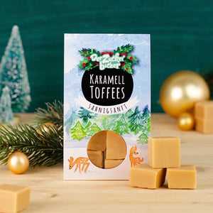 Packung Karamell-Toffees mit weihnachtlicher Dekoration und Tannenzweig.