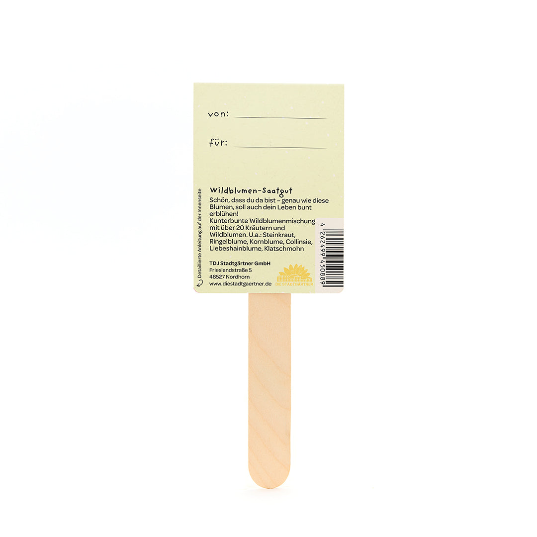 Rückseite eines Wildblumen-Saatgut-Sticks aus Holz mit gelbem Etikett und deutscher Beschreibung.
