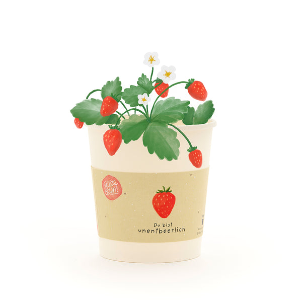 Ein cremefarbener Blumentopf mit einer gezeichneten Erdbeerpflanze, roten Erdbeeren und weißen Blüten, sowie der Aufschrift „Du bist unentbeerlich“.