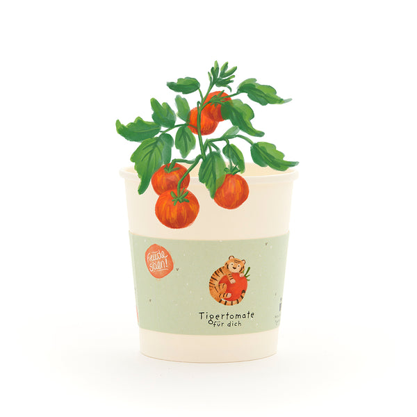 Becher mit einer kleinen Tomatenpflanze, auf dem Etikett steht „Tigertomate für dich“ und es ist ein gezeichneter Tiger mit Tomate abgebildet.