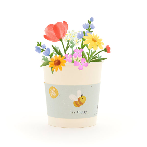 Blumentopf mit bunten Blumen und einer Biene auf dem Etikett mit der Aufschrift "Bee Happy".