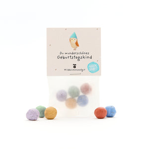 Tüte mit bunten Wildblumensamen-Bällchen und einer Geburtstagskarte mit der Aufschrift „Du wunderschönes Geburtstagskind“.