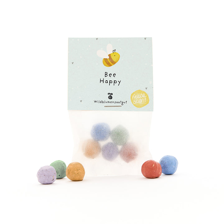Tüte mit bunten Samenbomben und Etikett "Bee Happy" sowie einer gezeichneten Biene.