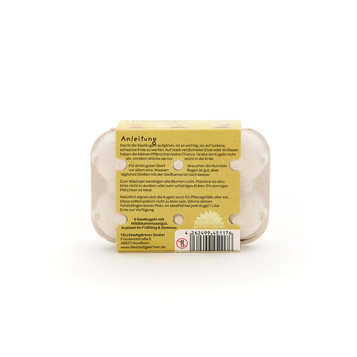 Rückseite einer kleinen Eierkartonverpackung mit aufgeklebter Anleitung zur Aussaat von Samen, Barcode und Herstellerinformationen auf Deutsch.