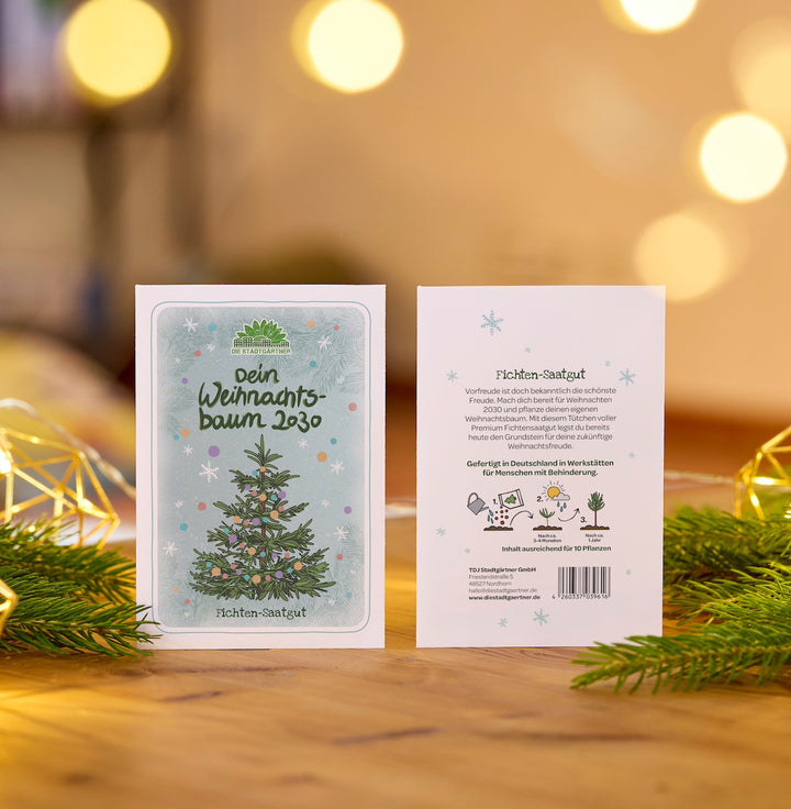 Zwei Karten mit Fichten-Saatgut für den eigenen Weihnachtsbaum im Jahr 2030, dekorativ auf einem Holztisch mit Tannenzweigen und Lichterdekoration präsentiert.