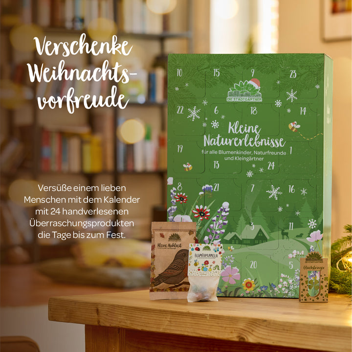 Großer grüner Adventskalender "Kleine Naturerlebnisse" mit weihnachtlichem Design, umgeben von kleinen Samentütchen, im gemütlich dekorierten Wohnzimmer.