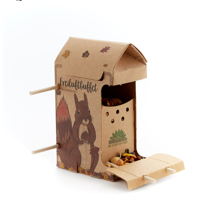 Papp-Futterspender mit Eichhörnchen-Motiv und der Aufschrift "Freiluftbuffet", gefüllt mit Nüssen und Samen.