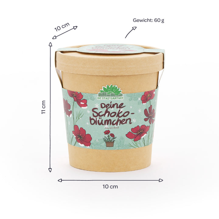Pappbecher mit Blumenmotiv und der Aufschrift „Deine Schokoblümchen“, daneben Maße (10 cm Durchmesser, 11 cm Höhe) und Gewicht (60 g) auf Deutsch angegeben.