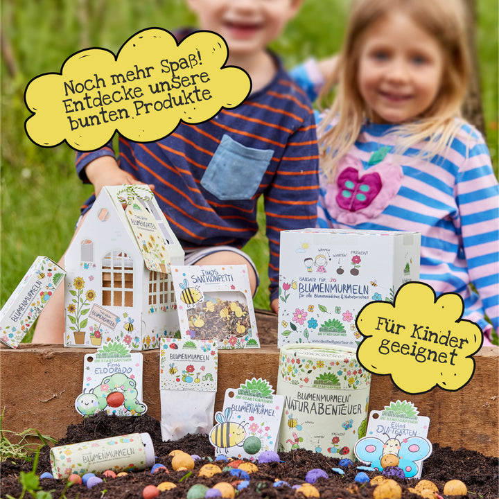 Zwei Kinder sitzen im Garten hinter einer Auswahl bunter Blumenprodukte mit spielerischen Verpackungen; gelbe Sprechblasen mit Text „Noch mehr Spaß! Entdecke unsere bunten Produkte“ und „Für Kinder geeignet“ ergänzen das Bild.