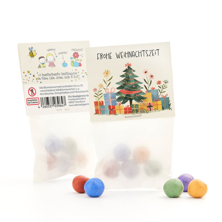Geschenkverpackung mit Weihnachtsmotiv und bunten Saatkugeln in Blau, Lila, Grün, Gelb und Rot.