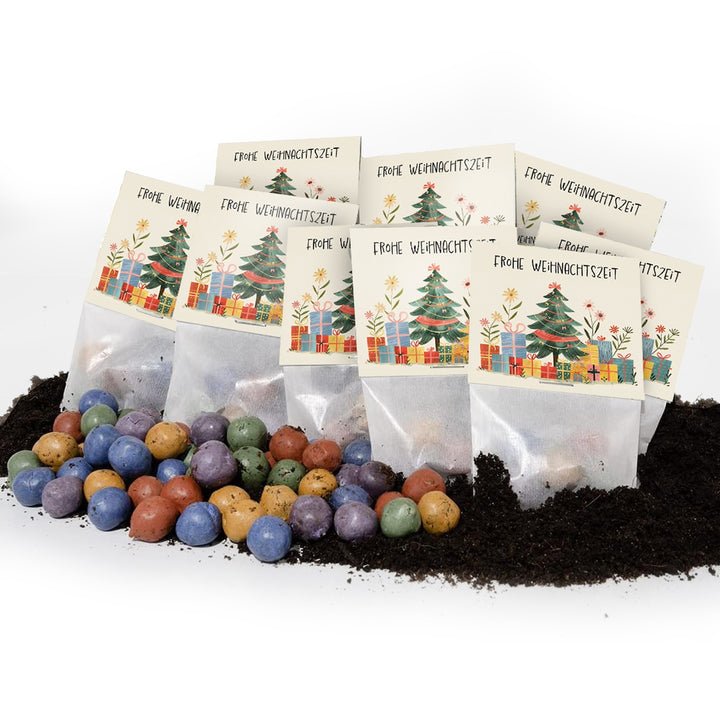 Mehrere Tütchen mit Weihnachtskarten mit der Aufschrift "Frohe Weihnachtszeit", im Vordergrund bunte Samenbomben und Erde.