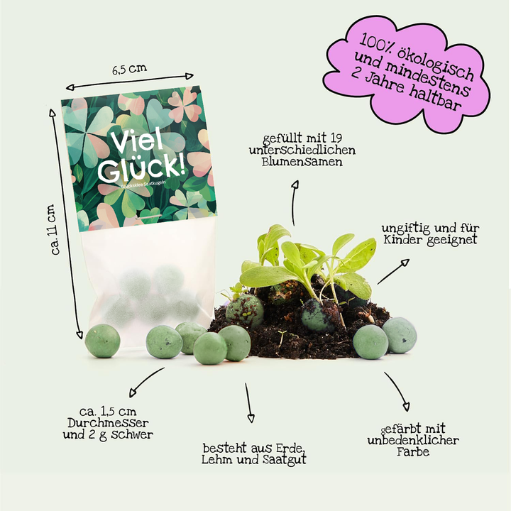 Tüte mit der Aufschrift "Viel Glück!", enthält grüne Samenbälle aus Erde, Lehm und Saatgut, die biologisch, ungiftig und für Kinder geeignet sind; daneben wachsen kleine Pflänzchen aus den Kugeln.