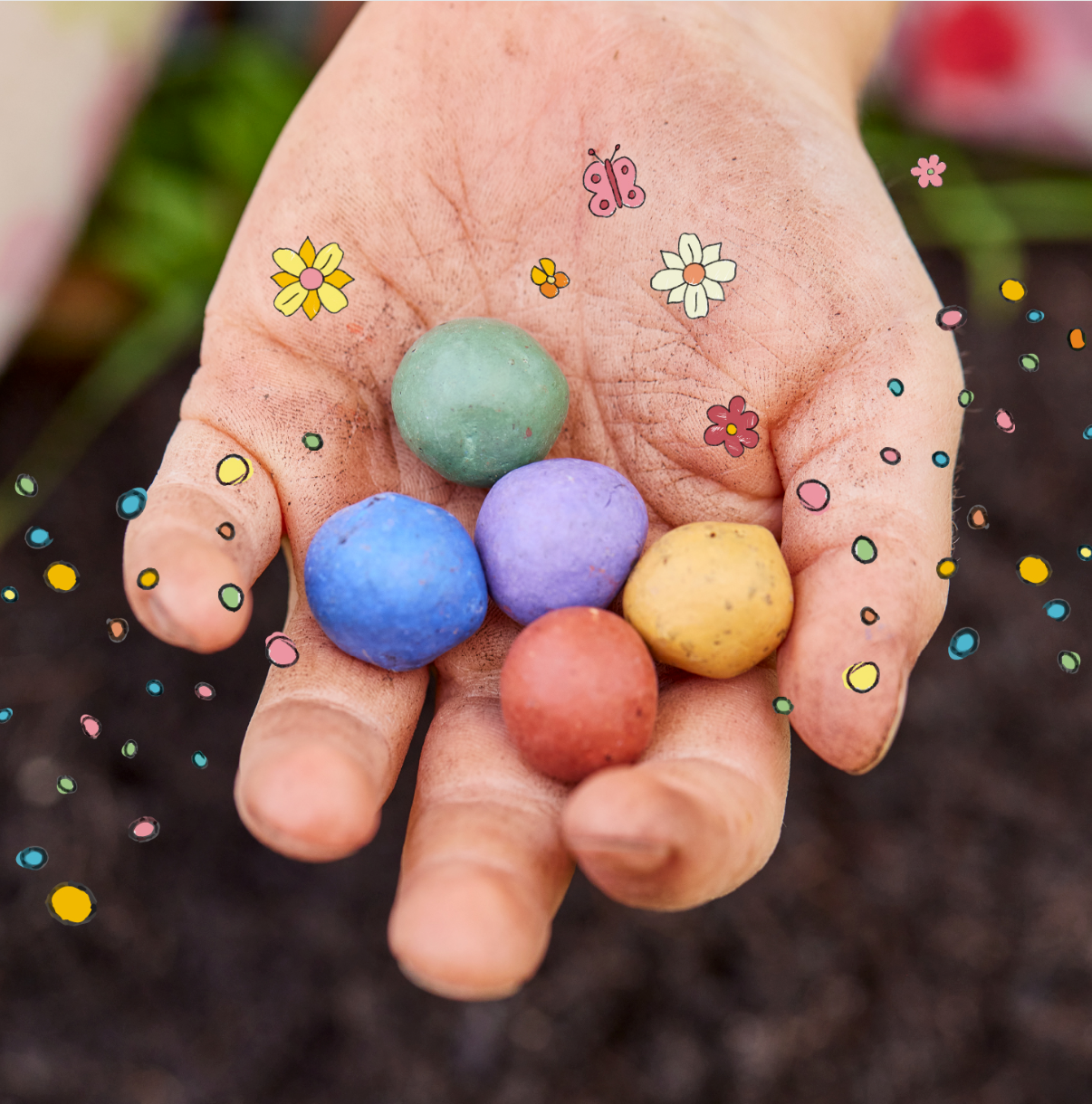 Eine Hand hält fünf bunte Samenbomben, umgeben von gezeichneten Blumen und Punkten.