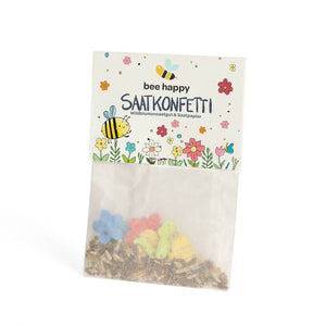 Tüte mit buntem Saatkonfetti und der Aufschrift "bee happy SAATKONFETTI Wildblumensaatgut & Saatpapier", verziert mit Bienen- und Blumenmotiven.