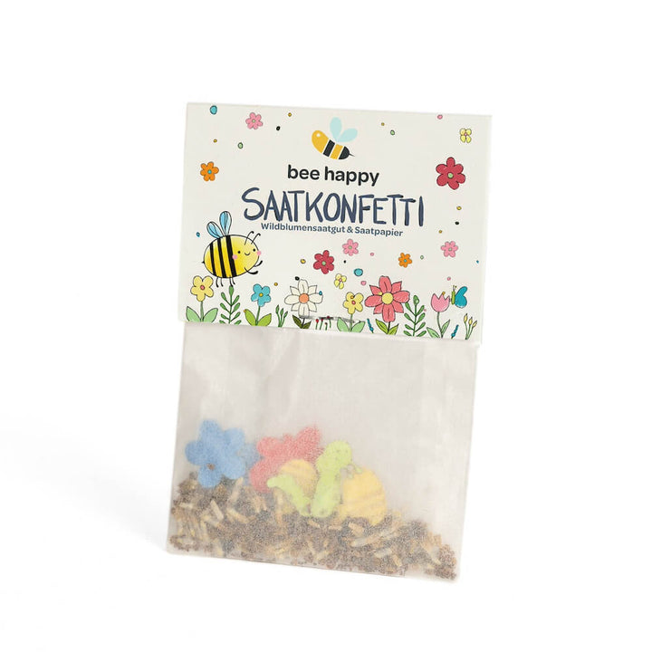 Tüte mit buntem Saatkonfetti und der Aufschrift "bee happy SAATKONFETTI Wildblumensaatgut & Saatpapier", verziert mit Bienen- und Blumenmotiven.