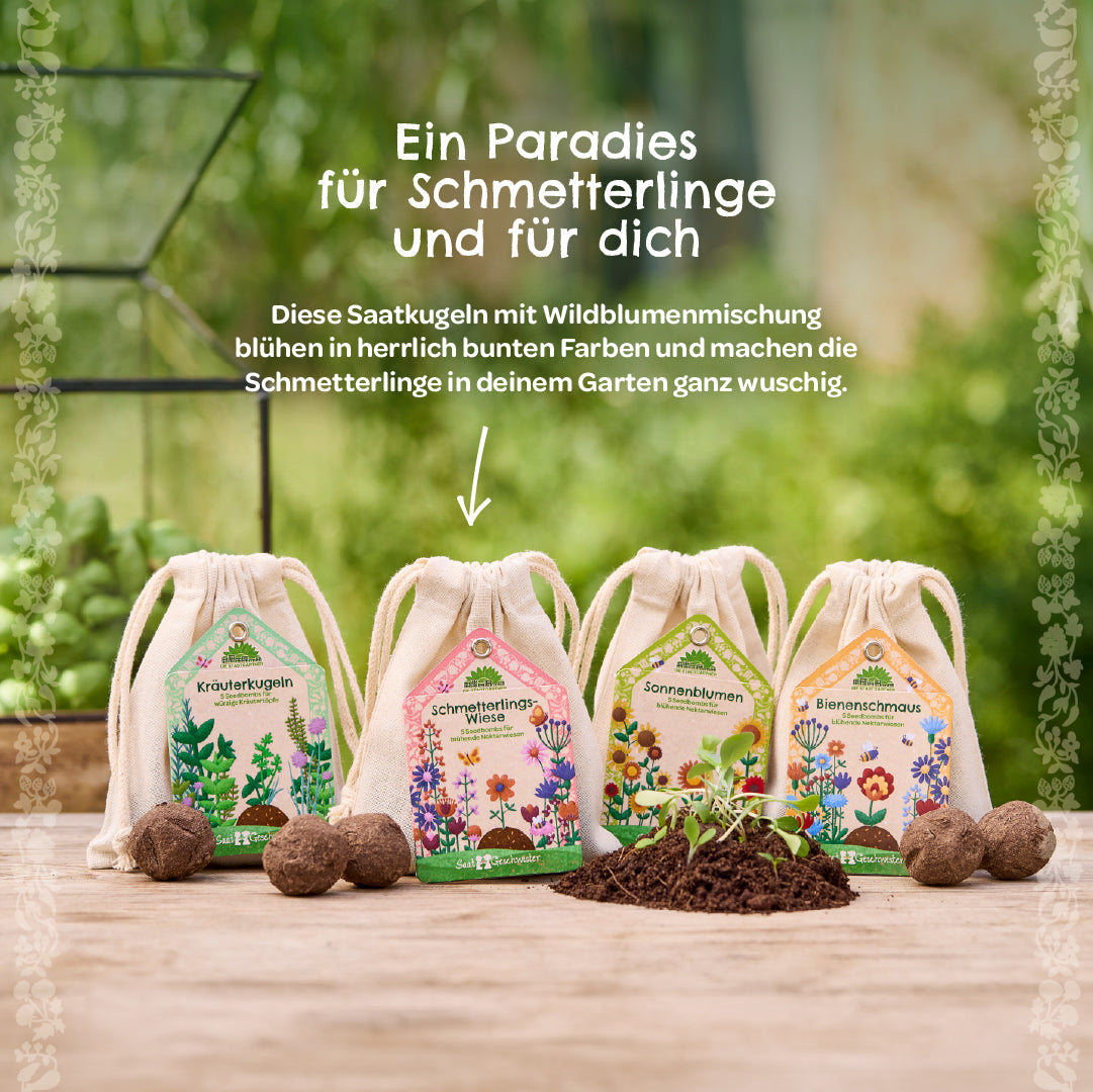 Vier Säckchen mit Saatkugeln aus Wildblumenmischung stehen auf einem Holztisch im Garten; daneben liegen Erde und Saatkugeln.