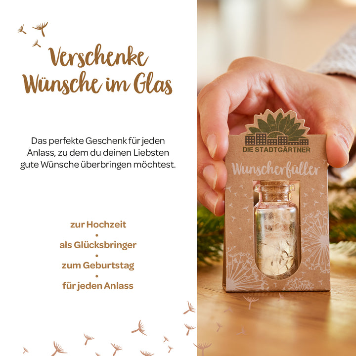 Person hält eine kleine Geschenkkarte mit der Aufschrift "Wunscherfüller" und einem kleinen Glasfläschchen, umgeben von saisonaler Dekoration und Text, der Geschenkideen für verschiedene Anlässe präsentiert.