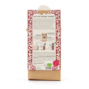 Rückseite einer Verpackung mit einer Anleitung zum Anpflanzen von Chili, umgeben von rotem, blumigem Muster, mit Text und Illustrationen auf Deutsch.