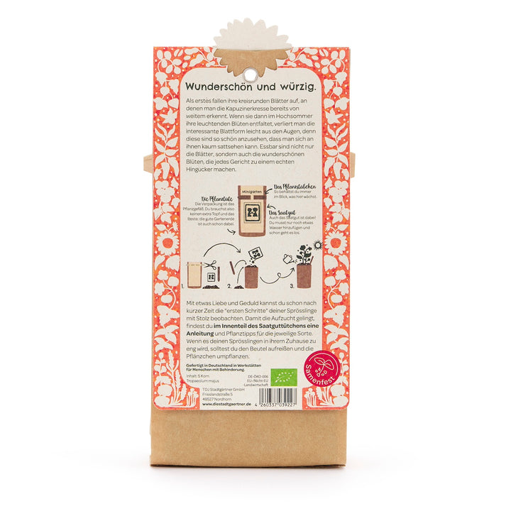 Rückseite einer Saatgut-Verpackung mit deutscher Beschreibung, Illustrationen zur Aussaat und orange-weißem Blumenmuster.