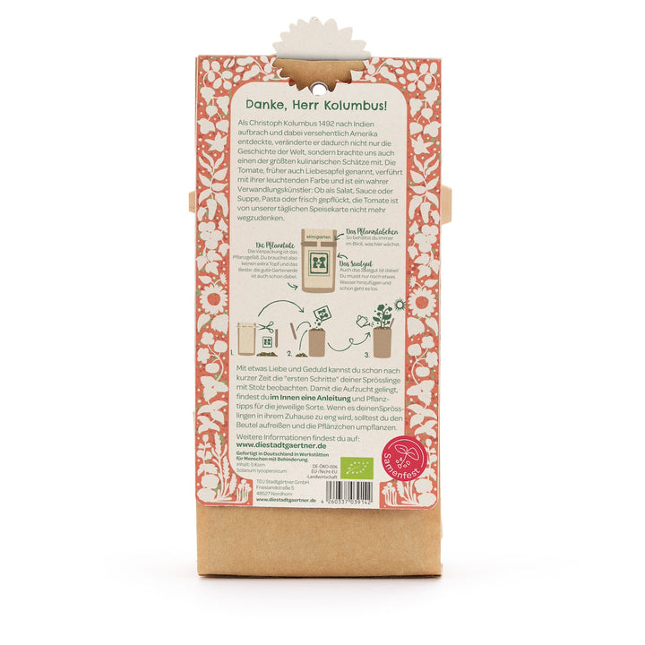 Rückseite einer Verpackung mit einer Anleitung zum Pflanzen von Tomaten, umgeben von einem roten Blumenmuster und deutschen Erklärungstexten.