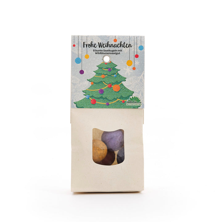 Tüte mit bunten Saatkugeln, weihnachtlich verpackt mit einem Etikett, das einen geschmückten Weihnachtsbaum und die Aufschrift "Frohe Weihnachten" zeigt.