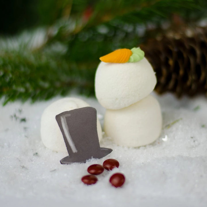 Ein Schneemann aus Marshmallows mit einem Zylinderhut und Karottennase auf schneebedecktem Untergrund.