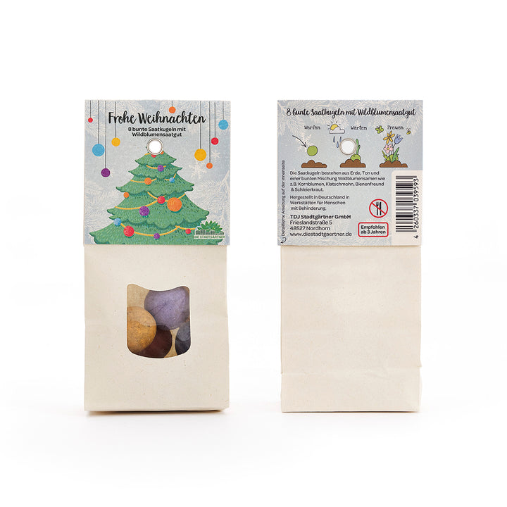 Zwei Packungen mit bunten Saatkugeln und Wildblumensaatgut, vorne mit Weihnachtsbaum-Illustration und der Aufschrift "Frohe Weihnachten".