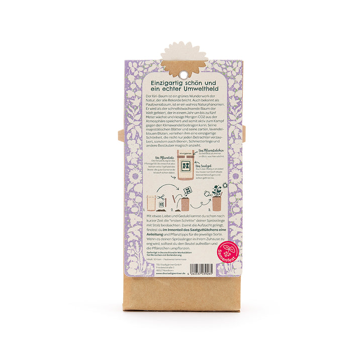 Rückseite einer Verpackung mit lila Blumenmuster, Text zur Umweltfreundlichkeit des Kiribaums, Anleitung zum Pflanzen, und Samenfest-Logo unten rechts.
