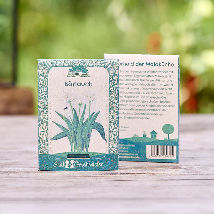 Zwei Samenpäckchen für Bärlauch von "Die Stadtgärtner" mit botanischer Illustration, auf einem Holztisch im Freien.