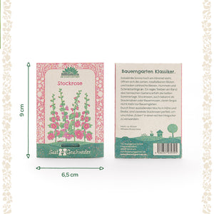 Zwei Samentütchen für Stockrosen von Saatgeschwister, eins mit Illustration der Blumen und eins mit Beschreibung auf Deutsch; Maße 9 cm hoch und 6,5 cm breit.