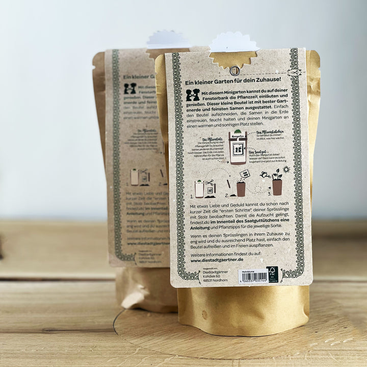 Zwei braune Papiertüten mit Anleitung für einen Minigarten auf der Rückseite, stehend auf einem Holztisch.