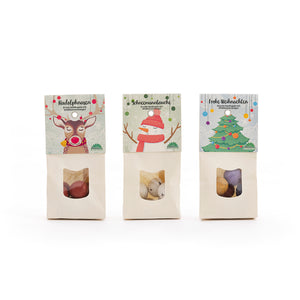Drei Weihnachtstüten mit Süßigkeiten, verziert mit Illustrationen eines Rentiers, eines Schneemanns und eines Weihnachtsbaums.