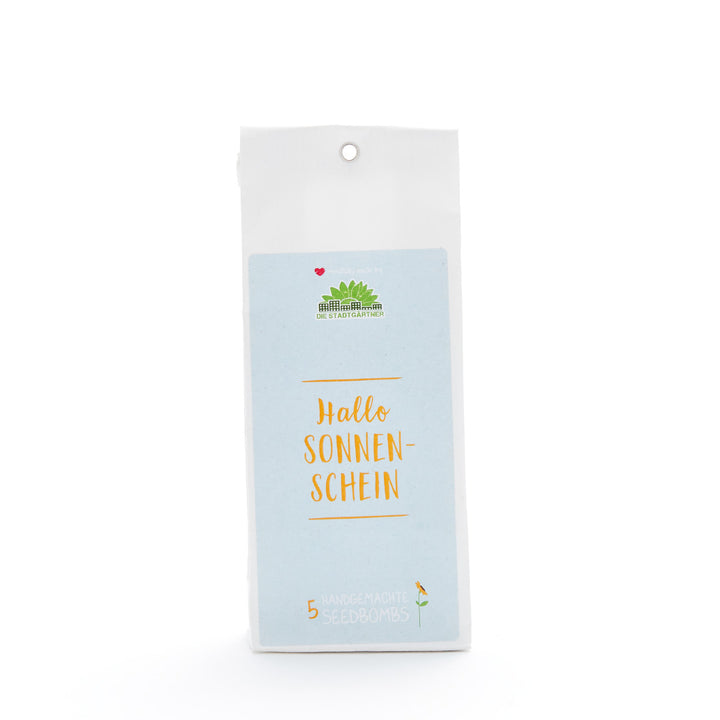 Verpackung von handgemachten Seedbombs mit dem Text "Hallo Sonnenschein" auf hellem Hintergrund.